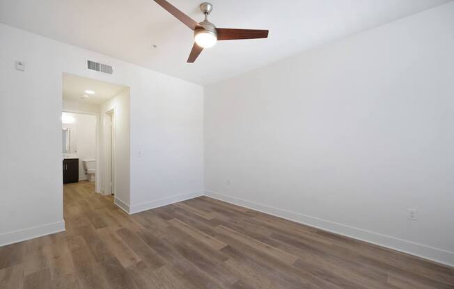 A room with a ceiling fan and wooden flooring.