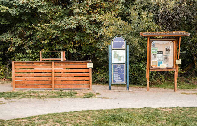 A signboard and a board with information are placed in front of a wooden gate.