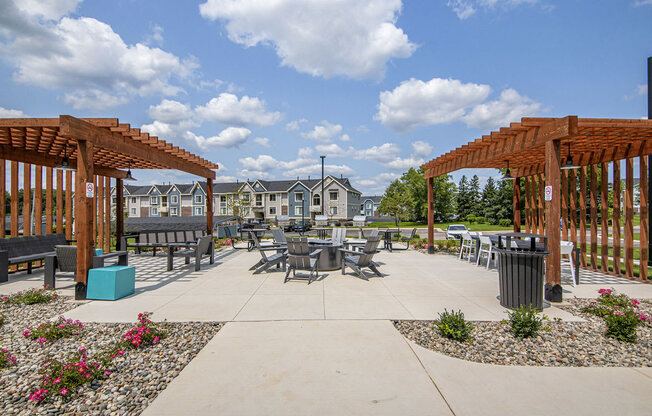 an outdoor pergola with tables and fire pit with seating at The Crossings Apartments, Michigan, 49508