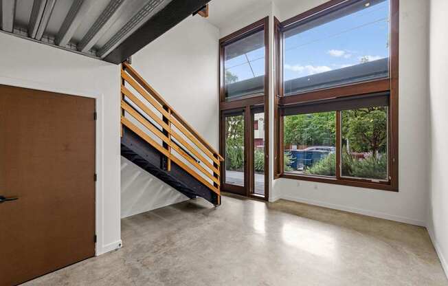 A room with a brown door and a staircase leading to a balcony.