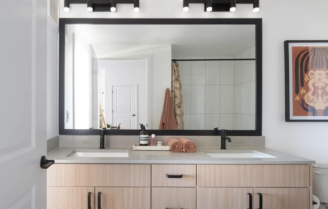 A spacious double vanity with light wood cabinetry, matte black accents, and generous counter space for an elevated daily routine.