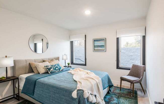 A bedroom with a bed, a chair, and a window overlooking a body of water.