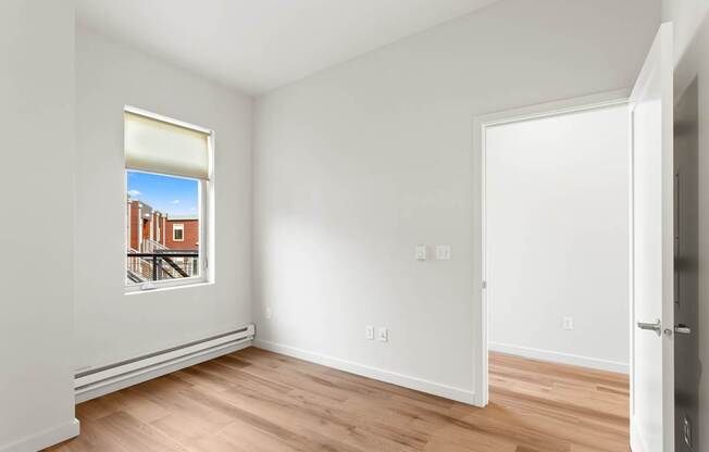 A room with a window showing a building outside.