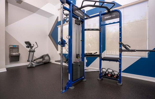 A gym with a blue and white color scheme and a SYNCLY 360 machine.