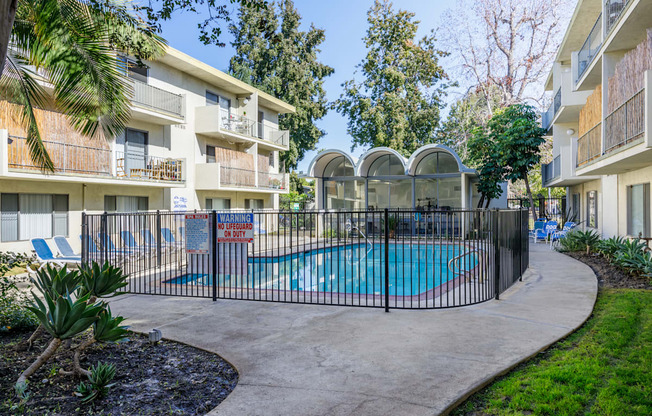 a swimming pool is behind a fence in front of an apartment building