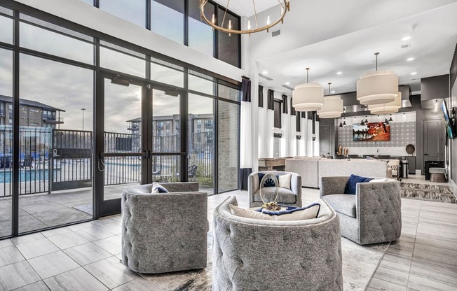 A modern living room with a large window and a view of a pool and buildings outside.