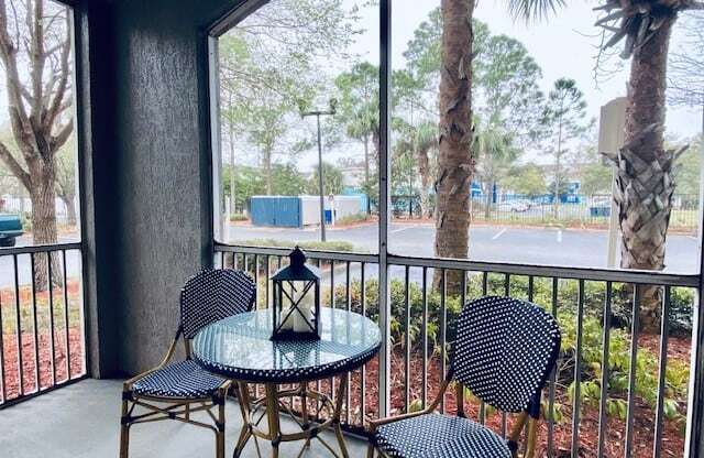 balcony with a table and chairs and a large window at Mainstreet Apartments, Clearwater, Florida