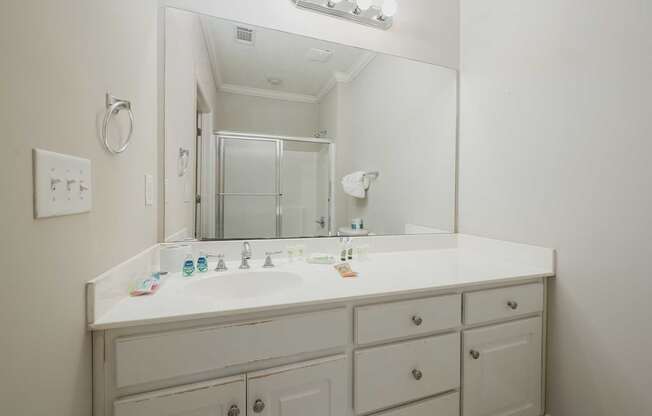 A white bathroom vanity with a mirror and lights above it.