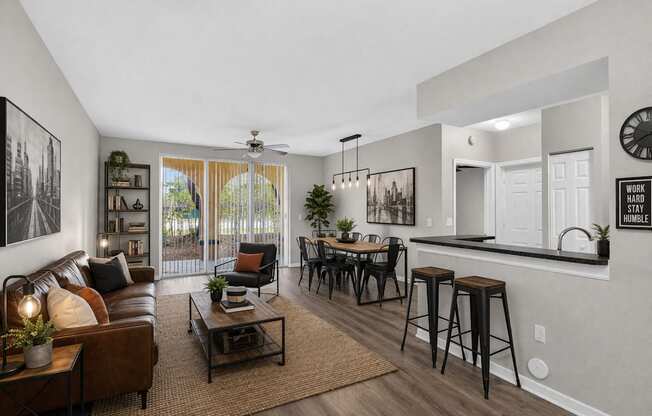 A living room with a brown leather couch, a coffee table, and a bar area with stools.