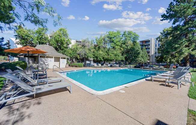 A swimming pool surrounded by trees and a building in the background.