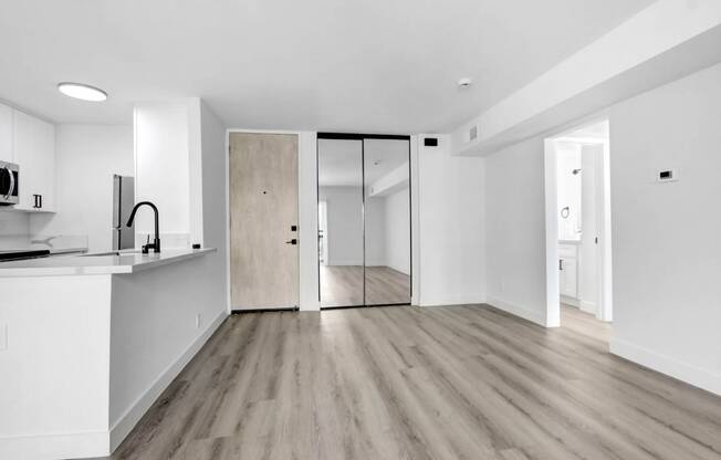 an empty living room with a kitchen and a sliding glass door