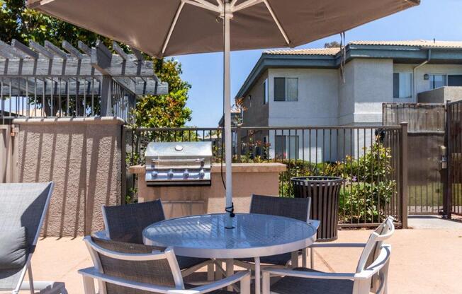 a patio with a table and chairs and a grill