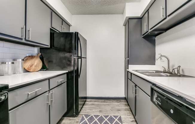 an empty kitchen with white counters and black appliances and a black refrigerator