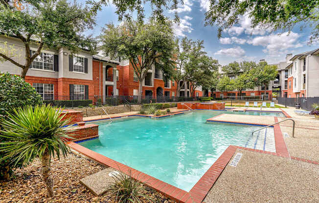 A swimming pool surrounded by a brick border and trees.