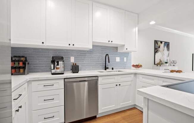 a white kitchen with stainless steel appliances and white cabinets