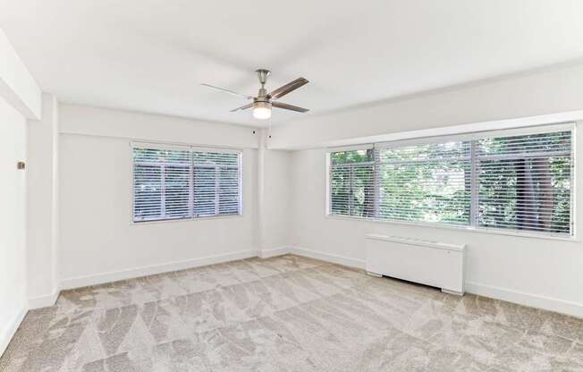 A room with a ceiling fan and a window with blinds.