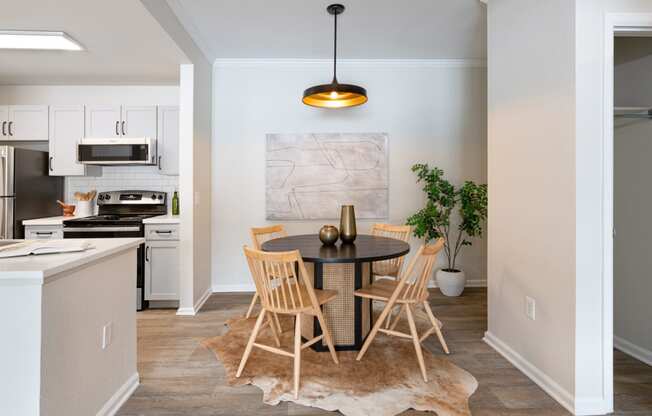 a dining area with a table and chairs and a kitchen in the background