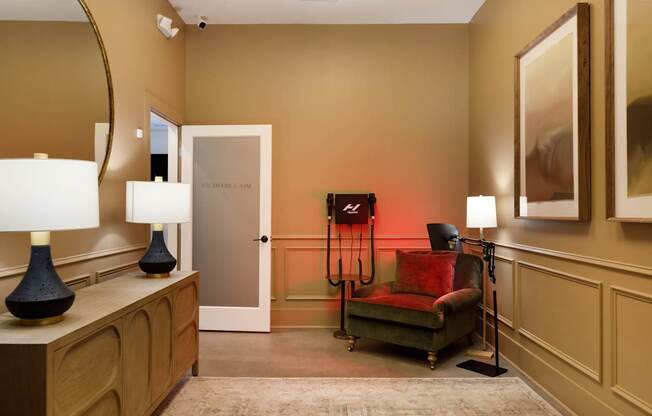 A room with a chair, a table, and a painting on the wall.