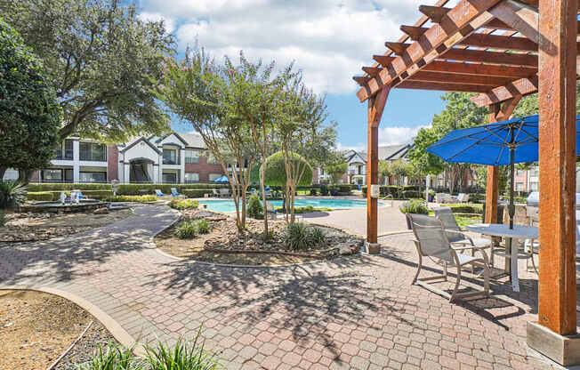 A patio with a table and chairs under a pergola.