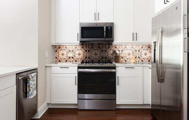 a white kitchen with stainless steel appliances and white cabinets