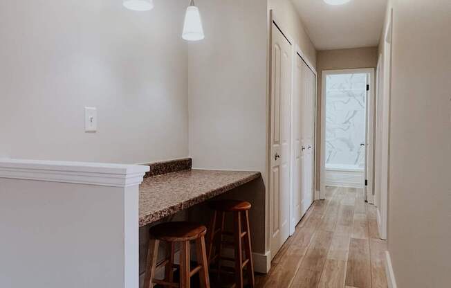A long hallway with a bar and stools on the left.