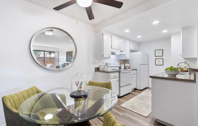 a white kitchen and dining room with a glass table