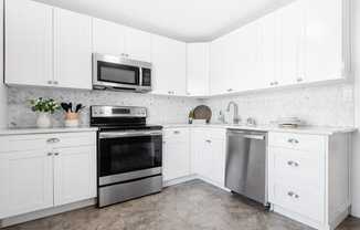 a white kitchen with stainless steel appliances and white cabinets