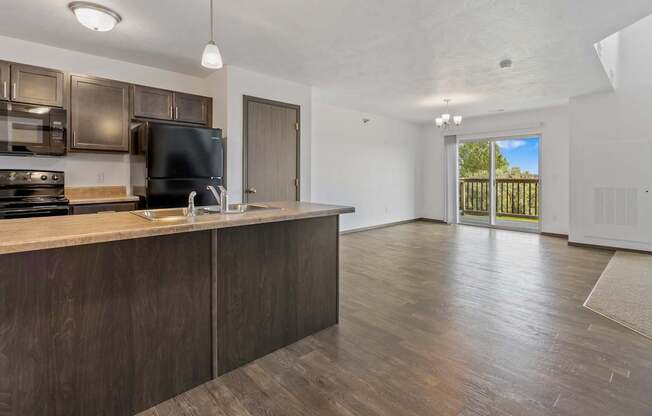 A kitchen with dark wood cabinets and a black fridge.