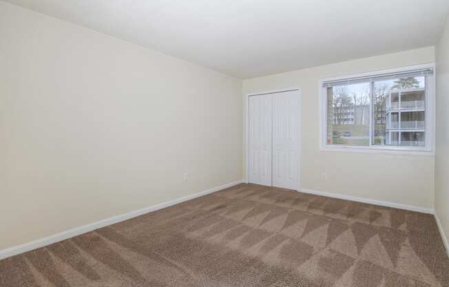 an empty living room with carpet and a window