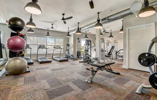 a gym with weights machines and lights on the ceiling