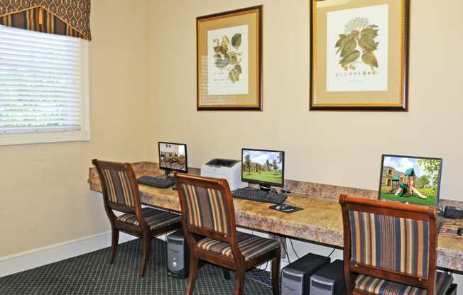 A room with a desk, chairs and pictures on the wall.