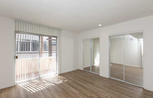 Bedroom with Mirrored Wardrobe Closet and Hardwood Floors