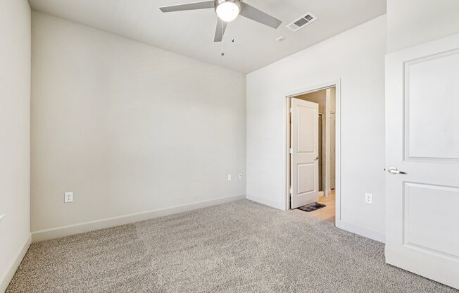 A room with a ceiling fan and carpeted floor.
