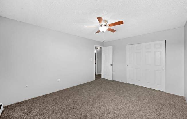 A room with a ceiling fan and carpeted floor.