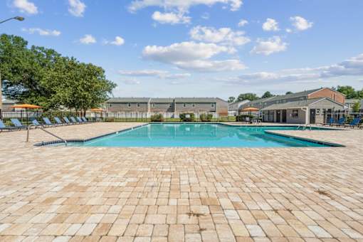 A large outdoor swimming pool surrounded by a brick patio at Staples Mill Townhomes Apartments, Richmond 23228
