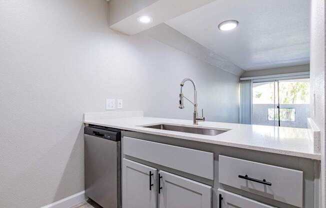 A white kitchen with a sink and a dishwasher.