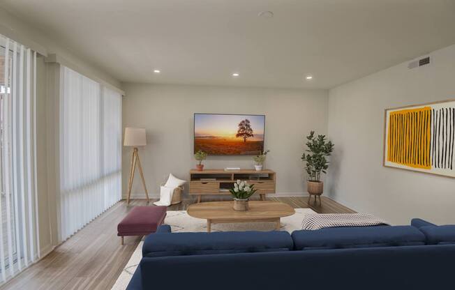 A modern living room with a blue sofa and a flat screen TV mounted on the wall.