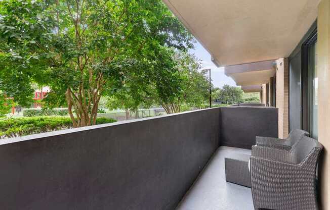 A balcony with a grey chair and a concrete wall.