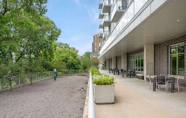 the terrace of a building with tables and chairs and trees