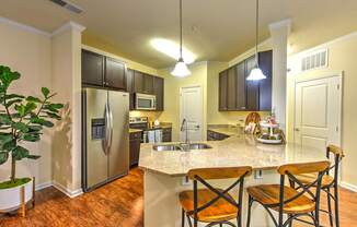 A kitchen with a refrigerator, microwave, oven, sink, and cabinets.