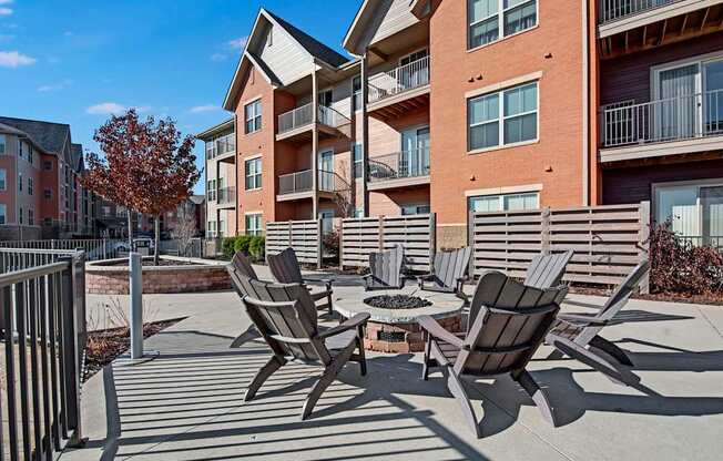 A landscaped outdoor courtyard here at Vue at Pinnacle Park with a central fire pit, surrounding lounge chairs, paved patio space, and nearby apartment balconies creating a relaxing community gathering area.