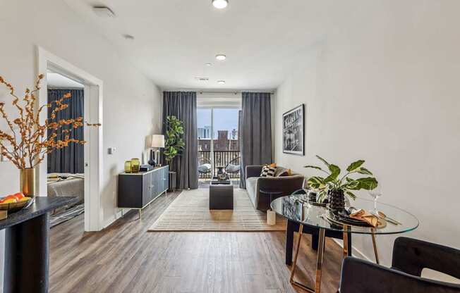 A modern living room with a glass table and black chairs.