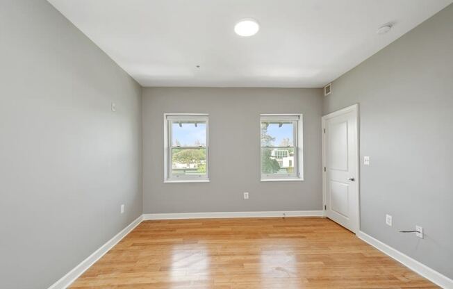 a room with a hardwood floor and three windows