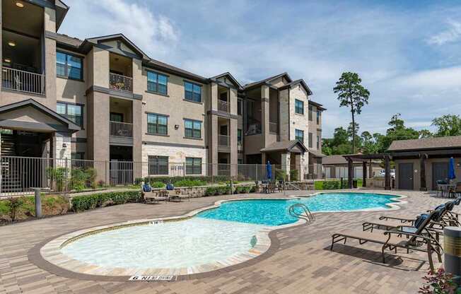 A large apartment complex with a pool in the middle of the courtyard.