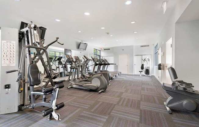 A gym with a variety of equipment including treadmills, weights, and exercise machines.
