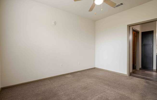 a bedroom with white walls and a ceiling fan and carpet at Parc at Bentonville Apartments in Bentonville, AR