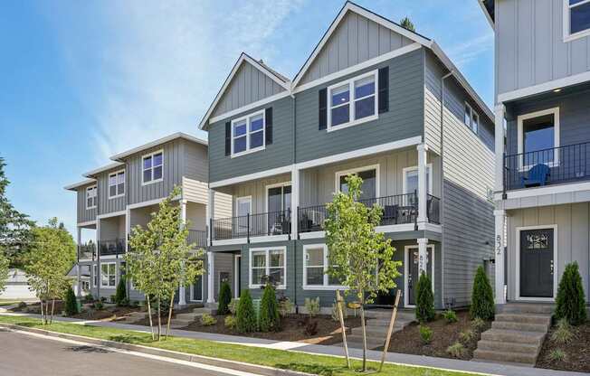 a row of houses with trees in front of them on a street