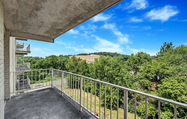 a balcony with a view of trees and a blue sky