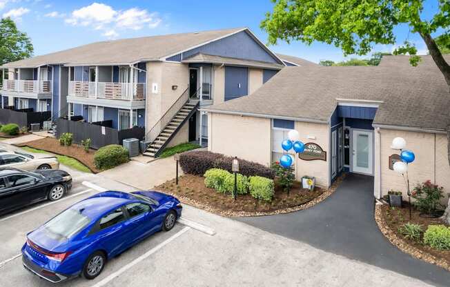A blue car is parked in front of a building with a sign that reads "2707".