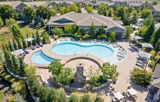 an aerial view of a resort style pool with chaise lounge chairs and umbrellas